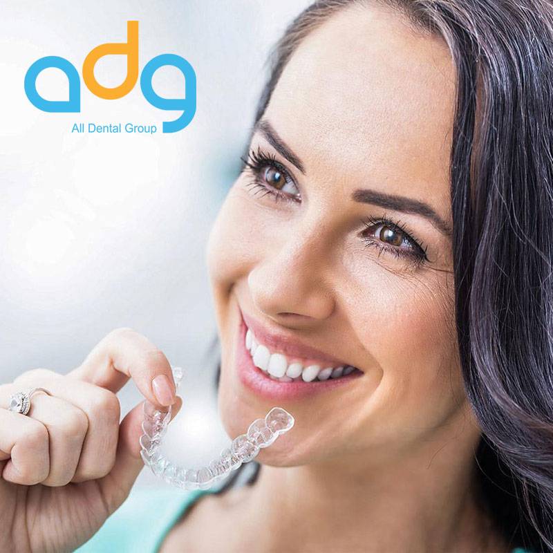 Happy woman with holding Invisalign braces and showing her perfect smile after treatment